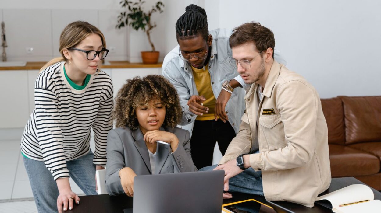 Students around a laptop giving advice to another student.